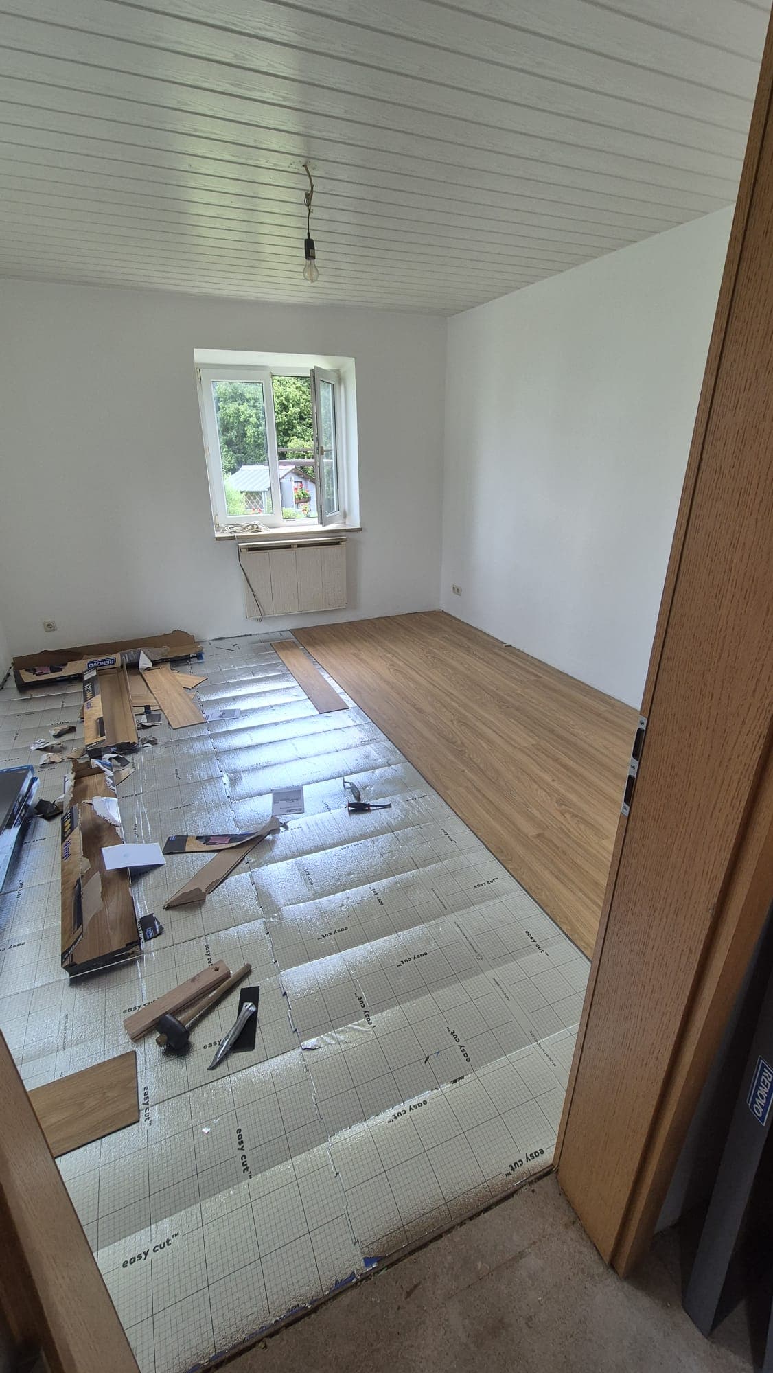 Wohnraum während der Verlegung: neue Trittschalldämmung und die ersten Laminatreihen