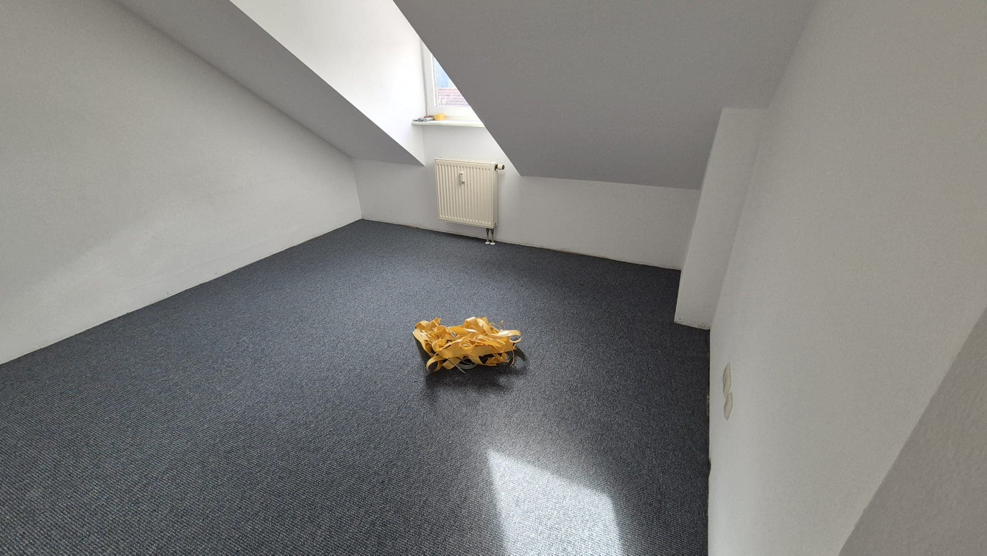 Zweites Dachgeschosszimmer mit fertig verlegtem grauem Teppichboden