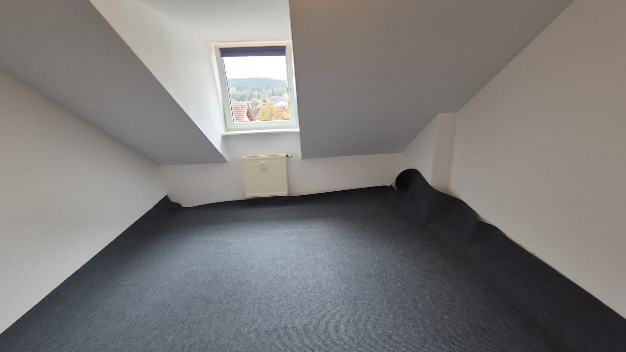 Neu verlegter grauer Teppichboden in einem Dachgeschosszimmer